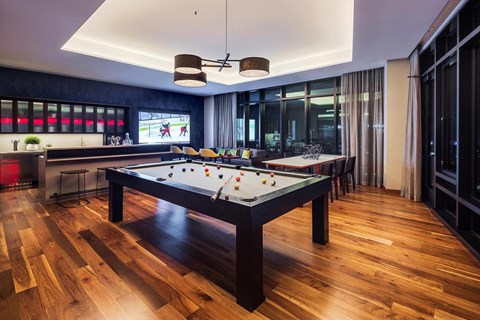 a pool table in a living room with a bar and television